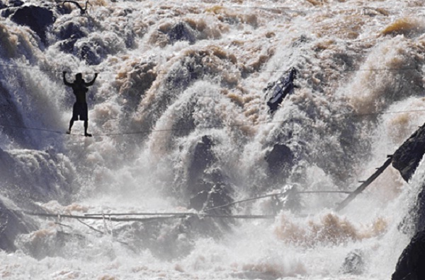 A daring fisherman crosses the Khon Phapheng falls on a wire that he and his friend built to access fishing areas during the rainy season (savethemekong.org)